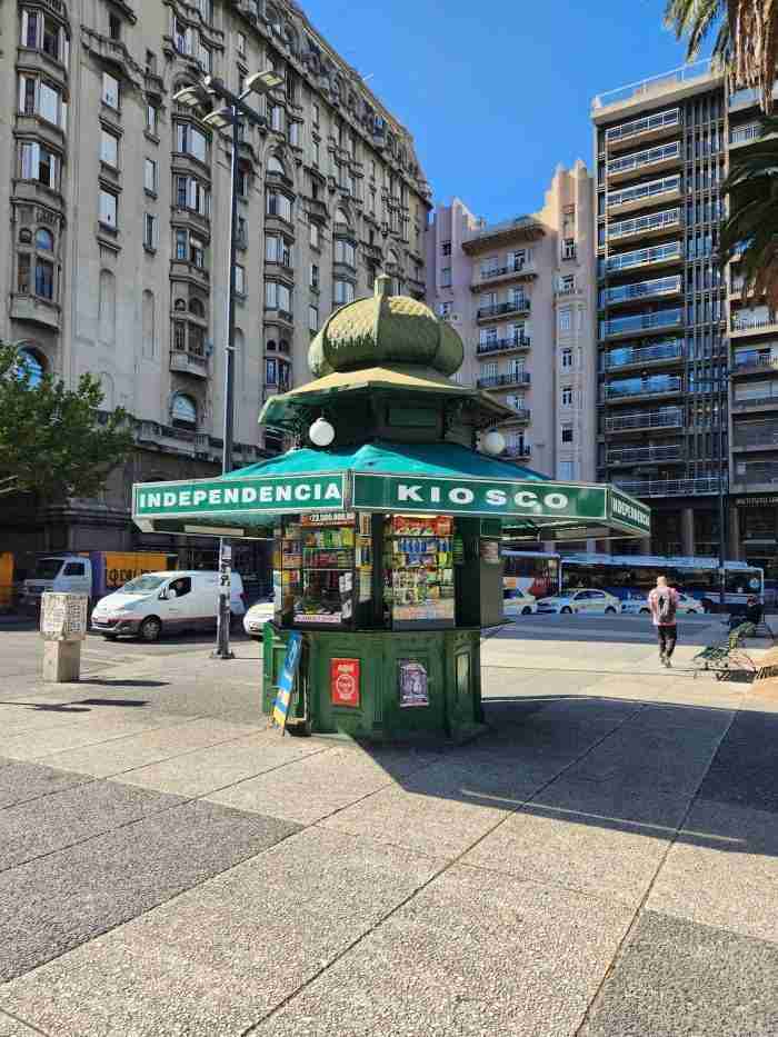 A green kiosk on a sidewalk Description automatically generated with medium confidence