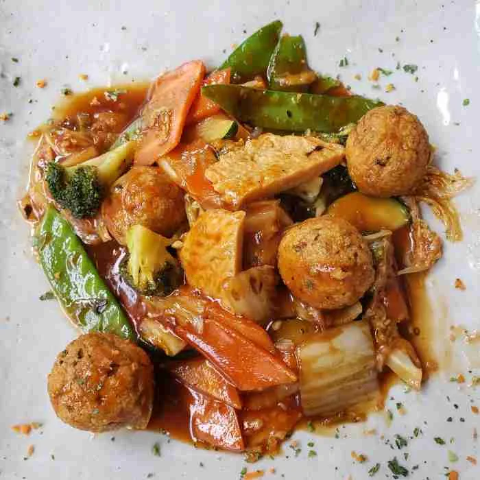 A close-up of Spicy Vegan “Meat Balls” and Soy “Chicken” in Garlic Sauce with various vegetables at Franchia Vegan Café. Photo by Sora Vernikoff