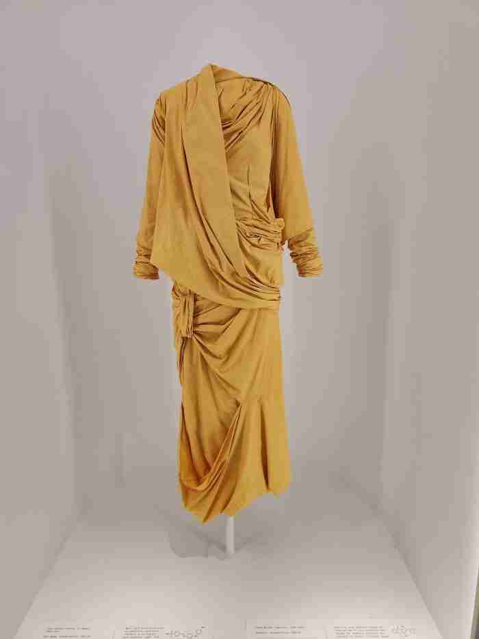 A yellow, wrap around dress on display at the Sleep Beauties: Reawakening Fashion exhibit at the Metropolitan Museum of Art in New York City. Photo by Sora Vernikoff