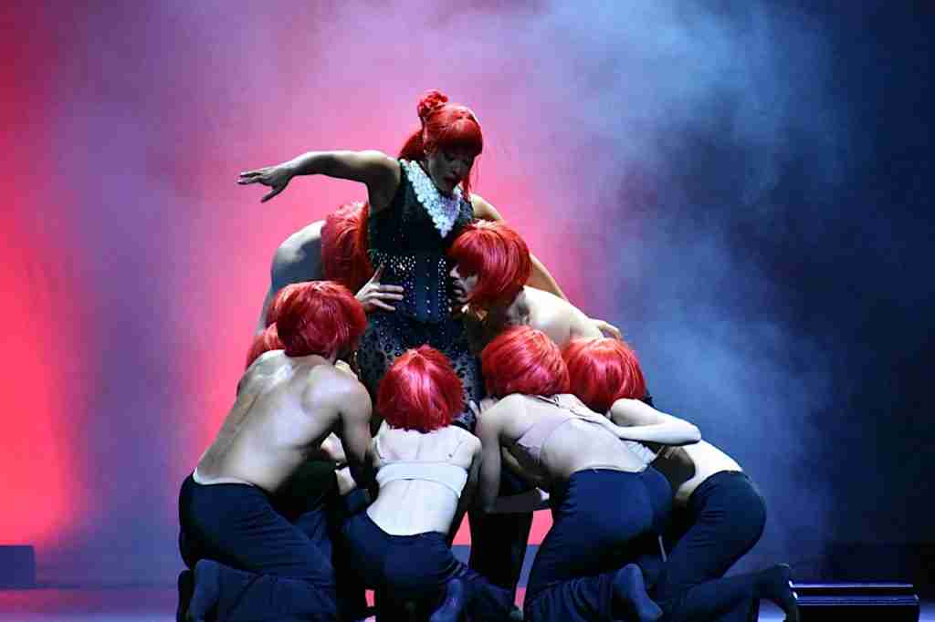 Ballet Hispánico’s commanding lead rises above a circle of dancers in red wigs during House of Mad’moiselle, captivating the Central Park SummerStage audience with theatrical flair and unity. Photo by Edward Kliszus