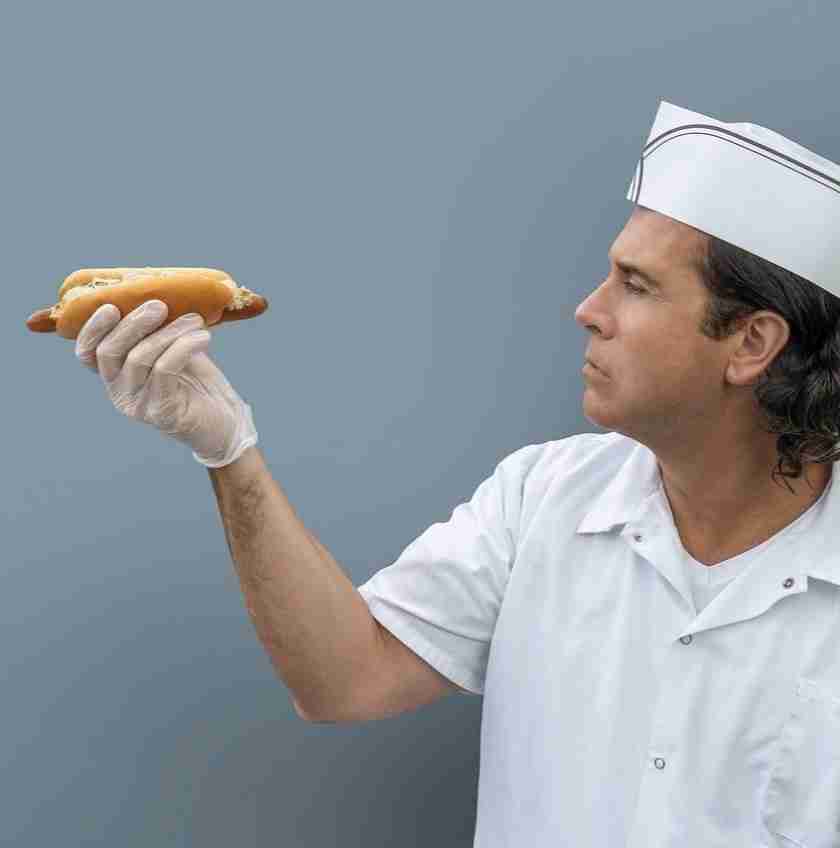 Michael Quinn, Star of Feltman: World First Hot Dog at The Chain Theatre, inspecting a Feltman Hot Dog. Photo by Mikiodo.
